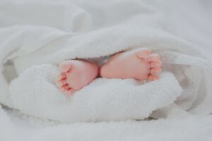bébé pieds nus couvrant une couverture blanche